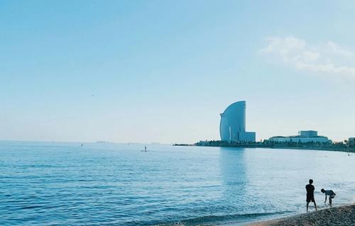 Barceloneta Beach with people sunbathing and the W Hotel in the background