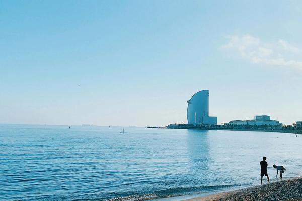 Barceloneta Beach with people sunbathing and the W Hotel in the background