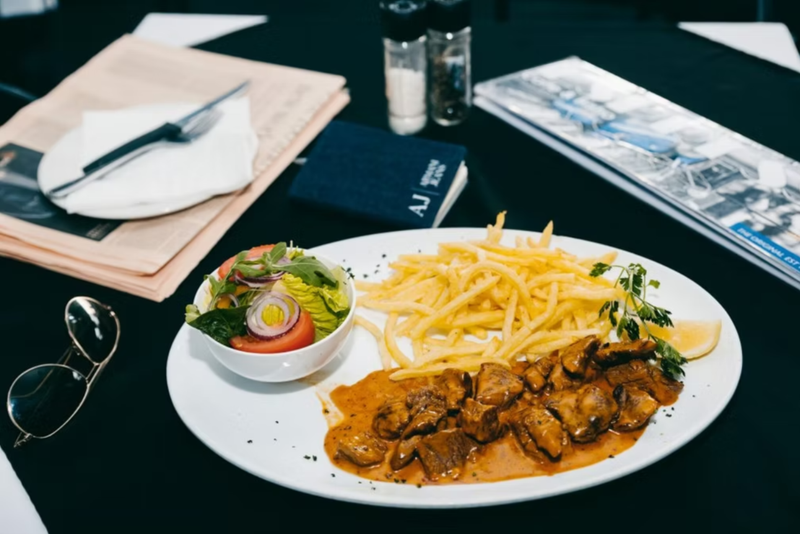 A plate of meat, chips, and salad on a café table