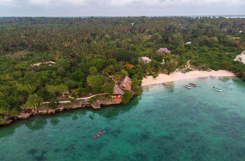 A kayak glides on blue ocean waters towards the shore of Zanzibar, one of the best East Africa holiday destinations.