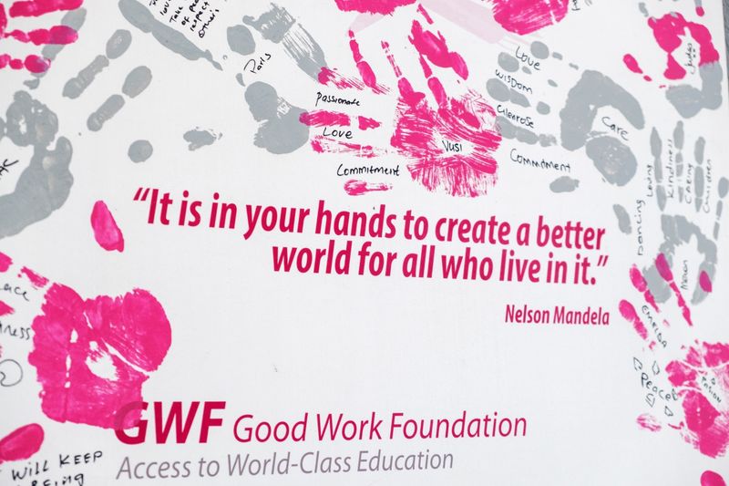 A powerful quote by Nelson Mandela is displayed on a wall, surrounded by vibrant pink and grey handprints, some of which have words of inspiration written within them.