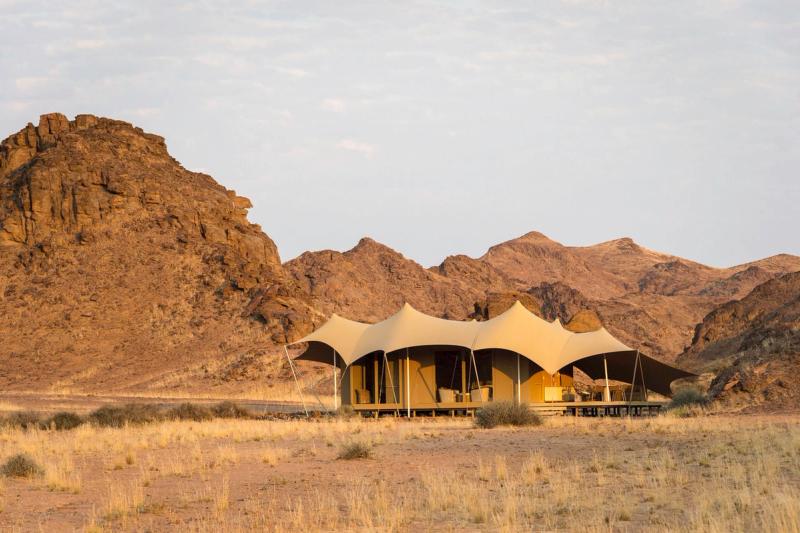 Ein Camp in der Wüste, dahinter eine Bergkulisse