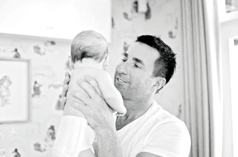 A father lifts his baby close, capturing a candid, early glimpse into fatherhood