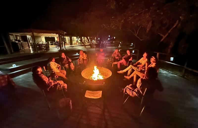 Guests gathered around a fire at a Gorongosa safari camp in the evening.