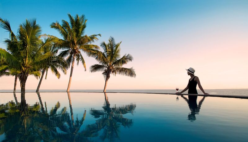 Swimming pool with palm trees, surrounded by scenic views