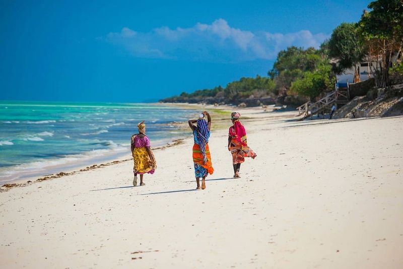 Frauen laufen an einem Strand auf Sansibar entlang