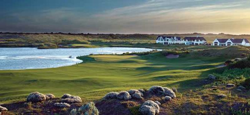 St Francis Links golf court, with a lake and small cottages on the background