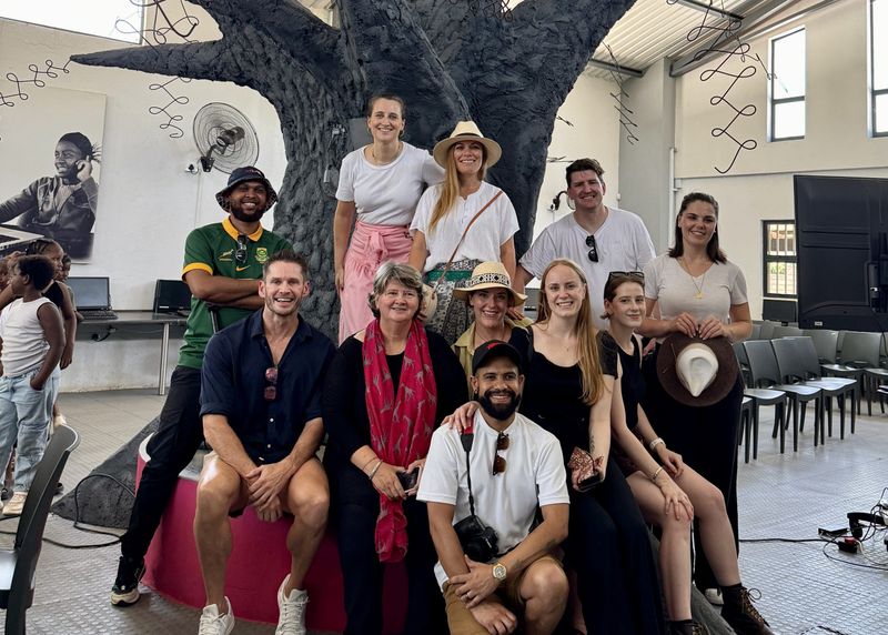 A group of smiling individuals from the Rhino Africa marketing team pose together in front of the striking tree sculpture at GWF, capturing a moment of connection and shared purpose.