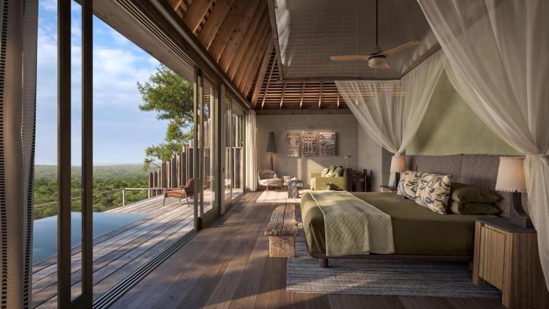 Amplia suite de safari con cama con dosel, terraza privada y vistas a la vegetación circundante.