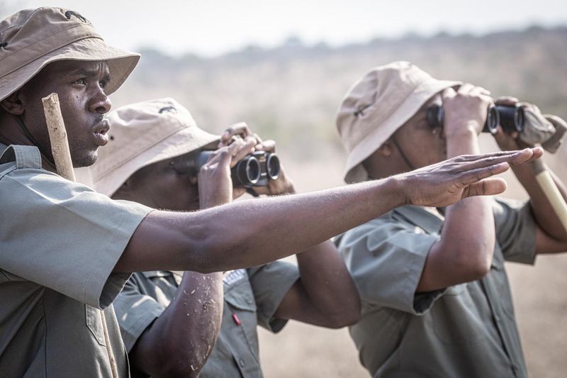 Tracker Academy Rhino Guardians using binoculars while surveying the landscape.