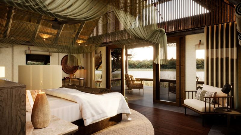 A spacious riverside suite features a draped canopy ceiling, soft natural textures, and an open deck overlooking the water.