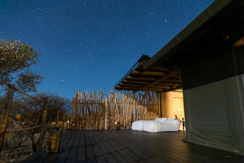 A large safari viewing deck with two loungers under a star-filled blue sky