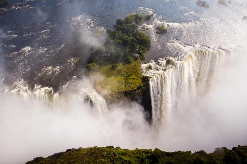 A curtain of water plunges off a mossy cliffside island, capturing the raw scale and energy of the best side of Victoria Falls.
