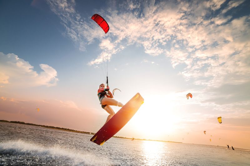 Woman kitesurfing with sunset and sea background