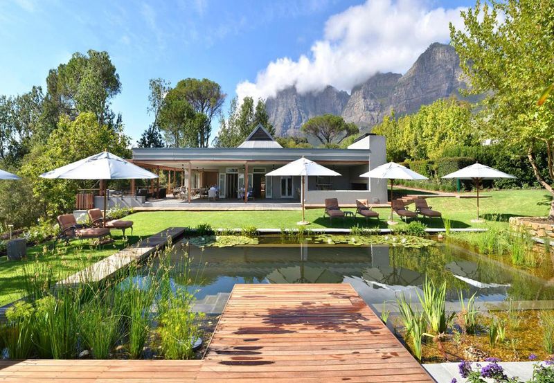 Eco pool with lillies, sun beds, umbrellas, and trees at Angala Hotel