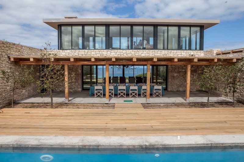 ein Pool, dahinter eine große Suite und ein großer Tisch