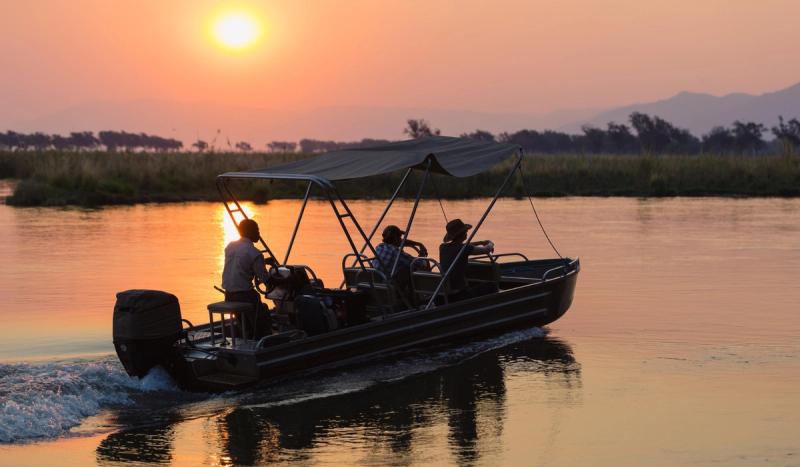 A small boat drifts along a glowing river at sunset, capturing a manifesto moment shaped by stillness and open water.