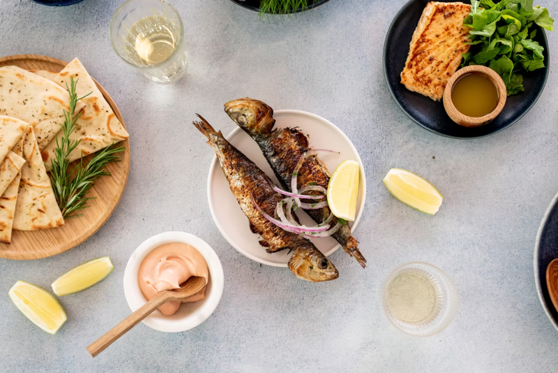 A table with fish and flatbread tapas with lemons and sauce