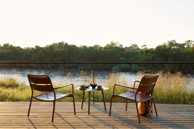 Two chairs and a table overlooking the river at Lion Sands River Lodge, Sabi Sand