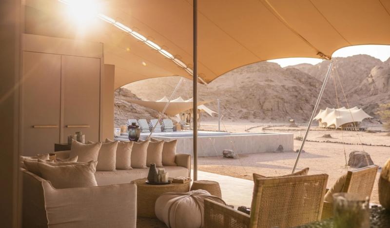A shaded lounge area opens onto a desert camp framed by rocky hills, setting the scene for where to go in 2026.