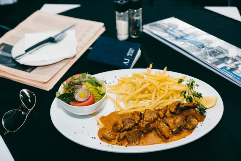 A plate of meat, chips, and salad on a café table
