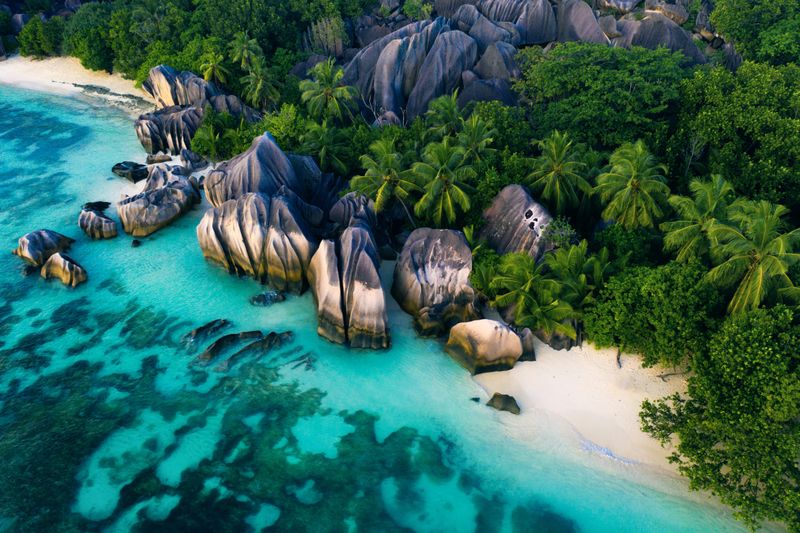 Turquoise waters lap against granite boulders and palm-fringed sands, reflecting the island beauty of Africa in September.