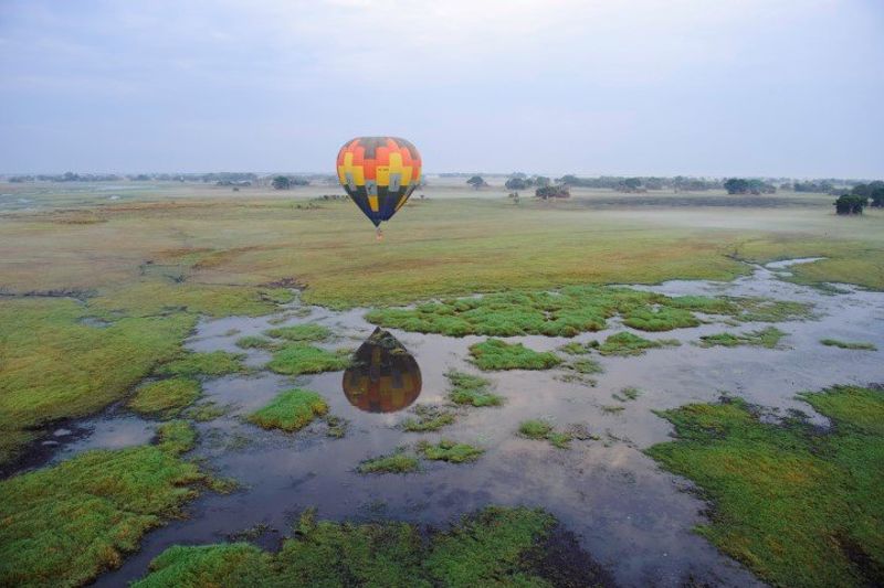 Ein bunter Heißluftballon fliegt über die traumhafte Landschaft Sambias