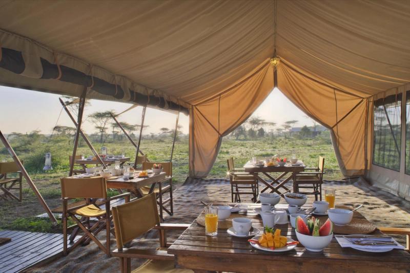 Breakfast is served inside one of Tanzania’s mobile tented camps, where canvas walls open to the plains and sunlight streams across fruit-laden tables.