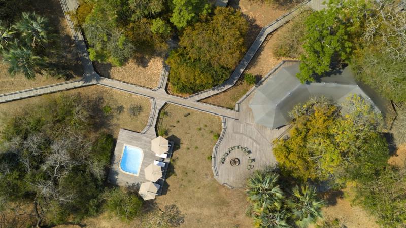 An aerial view shows Muzimu Lodge’s walkways, pool deck, and shaded main area during a Gorongosa safari.