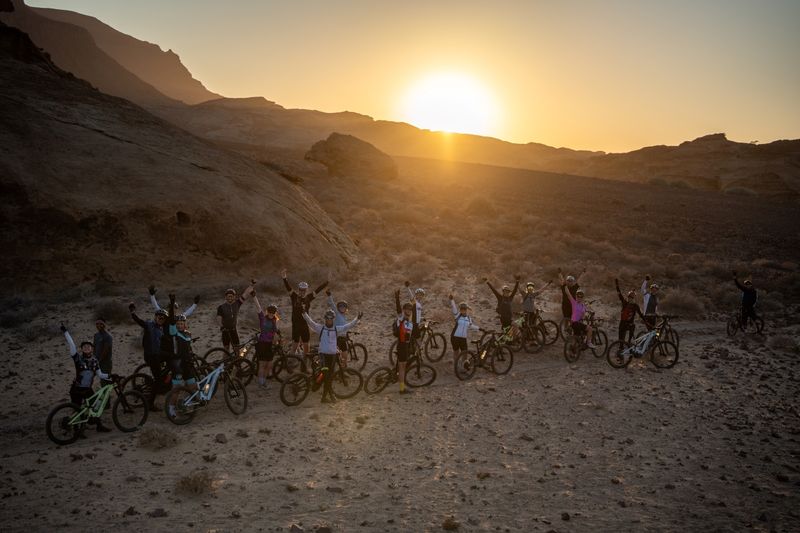 Cyclists lined up ready to get going with the sun rising in the background