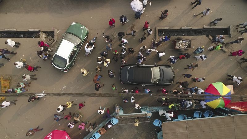 Street in Brazzaville with people, including sapeurs, and cars from a bird's eye view