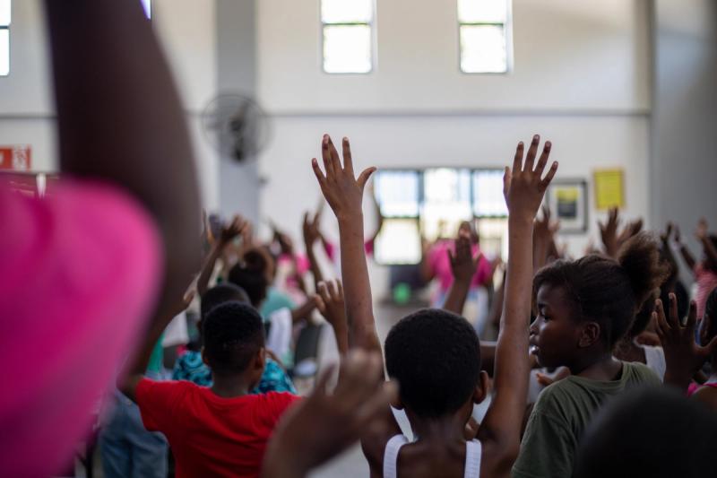 Students at the GWF Hazyview campus raise their hands in active engagement with their facilitator during a classroom session.