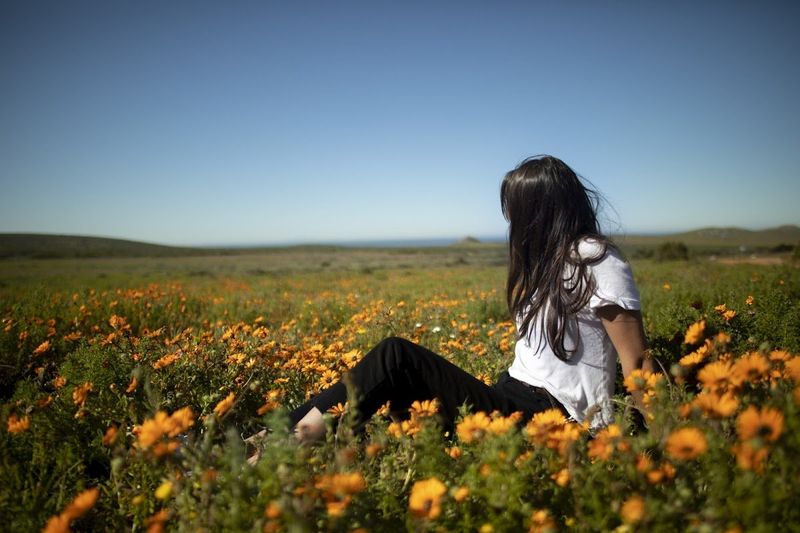 Une fille allongée dans un lit de fleurs orange.