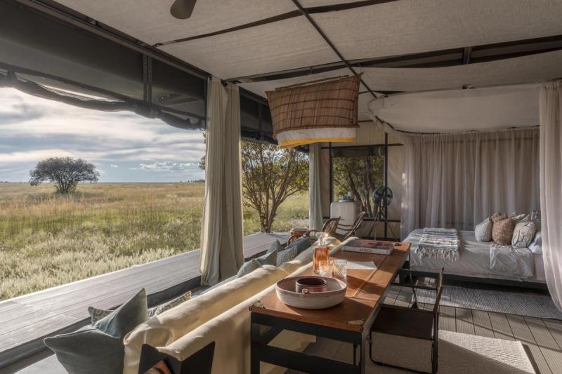 An open-sided safari tent reveals a softly furnished interior overlooking wide grasslands, embodying immersive destinations for responsible travel.