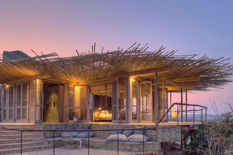 A lantern-lit suite at Jabali Ridge opens onto a wide wooden deck beneath a woven canopy, embodying the refined seclusion found at Luxury safari lodges in Tanzania.