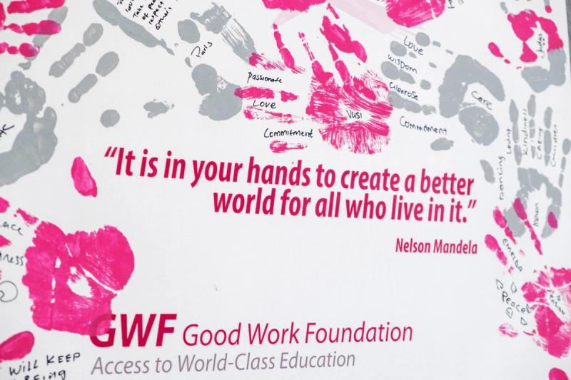 A powerful quote by Nelson Mandela is displayed on a wall, surrounded by vibrant pink and grey handprints, some of which have words of inspiration written within them.