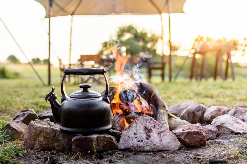 A blackened kettle sits above a campfire, showing how to stay present through smell, sound, and the slow promise of heat