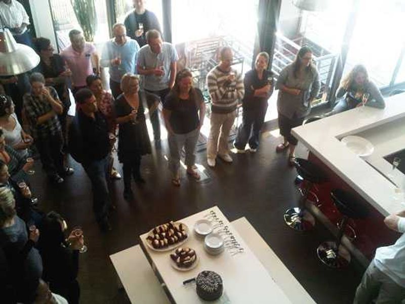 The team stand, champagne in hand, listening to David's words