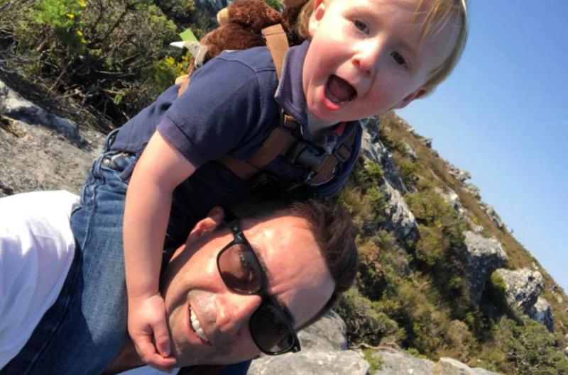 David gives his laughing child a shoulder ride while hiking