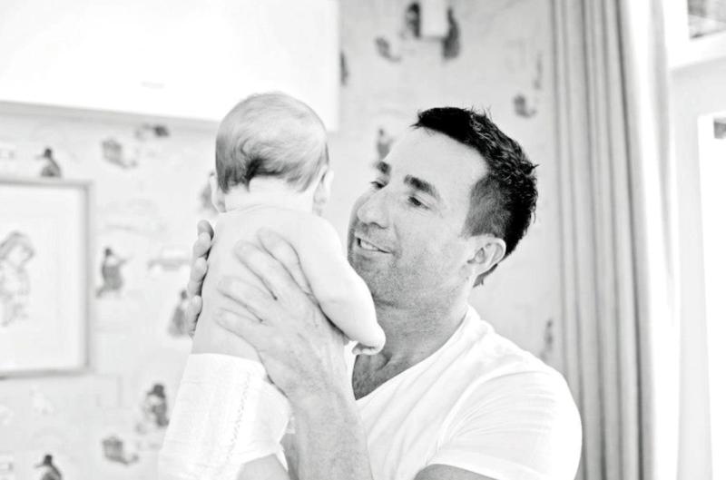 A father lifts his baby close, capturing a candid, early glimpse into fatherhood
