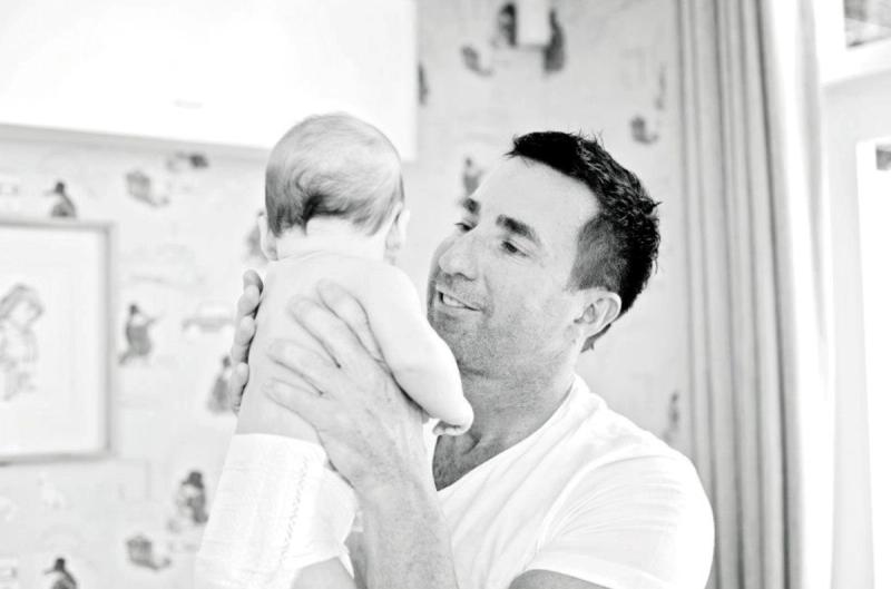 A father lifts his baby close, capturing a candid, early glimpse into fatherhood