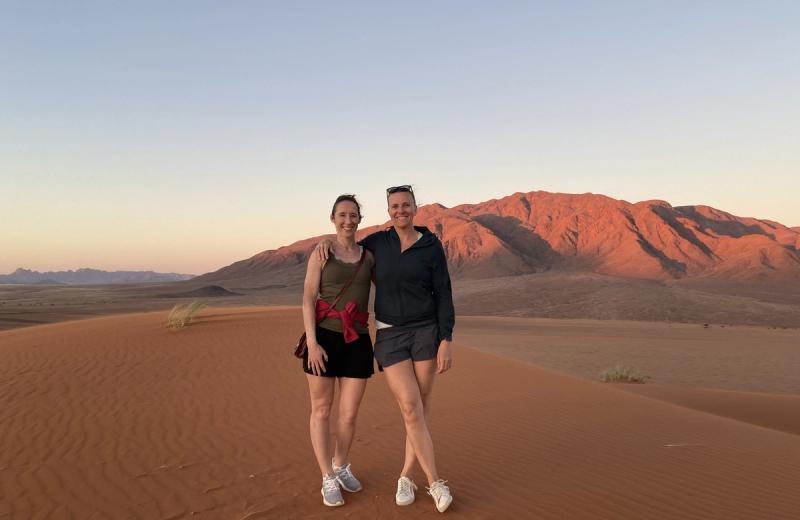 Peggy and Julia standing on a sand dune at sunset in the Namib Desert during their Namibia self-drive journey.