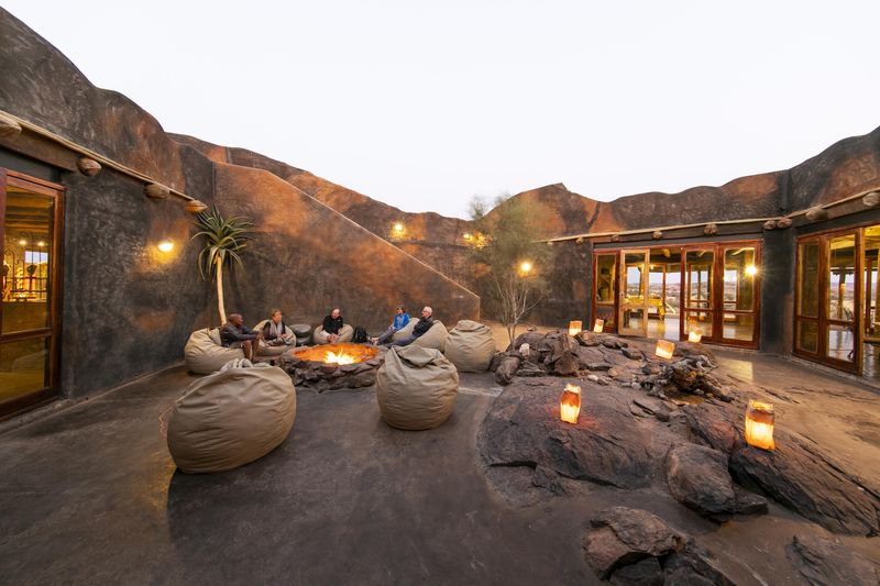 Guests enjoy a camp fire in the courtyard of one of the best luxury lodges in Namibia