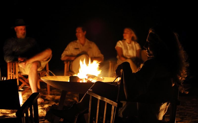 guests talking around a bonfire at Londolozi safari in South Africa