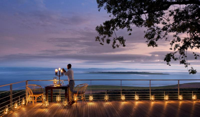 A staff member lights candles on a deck overlooking Lake Kariba at dusk, closing the scene on where to go in 2026.