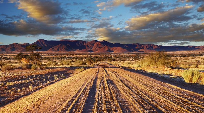 Empty desert road stretching through remote Namibian landscape in Kalahari Desert, Namibia