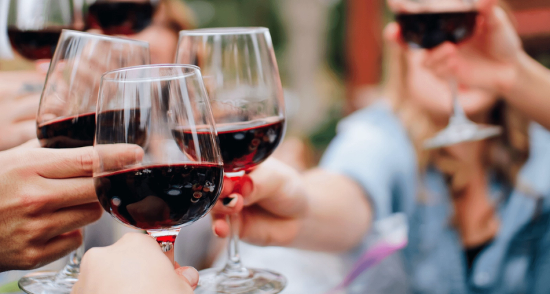Personen stoßen mit Rotwein an