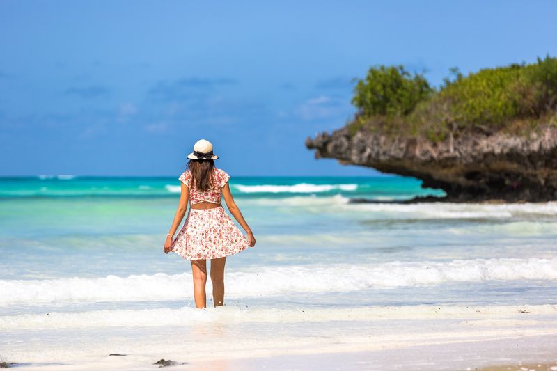 Woman testing idyllic crystal clear waters on a beach