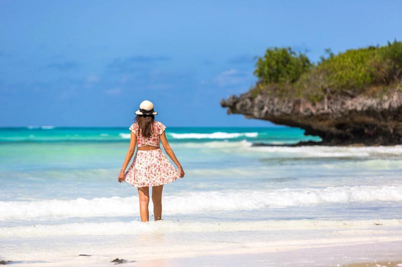 Woman testing idyllic crystal clear waters on a beach
