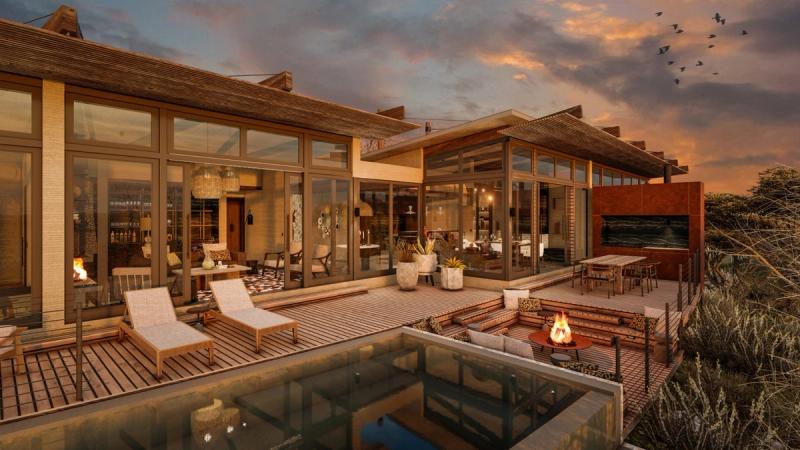A contemporary gorge-side suite opens onto a wide deck with sun loungers, a firepit, and a pool reflecting the evening sky at one of the new luxury safari lodges 2026.